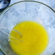 lemon dressing is whisked in glass mixing bowl