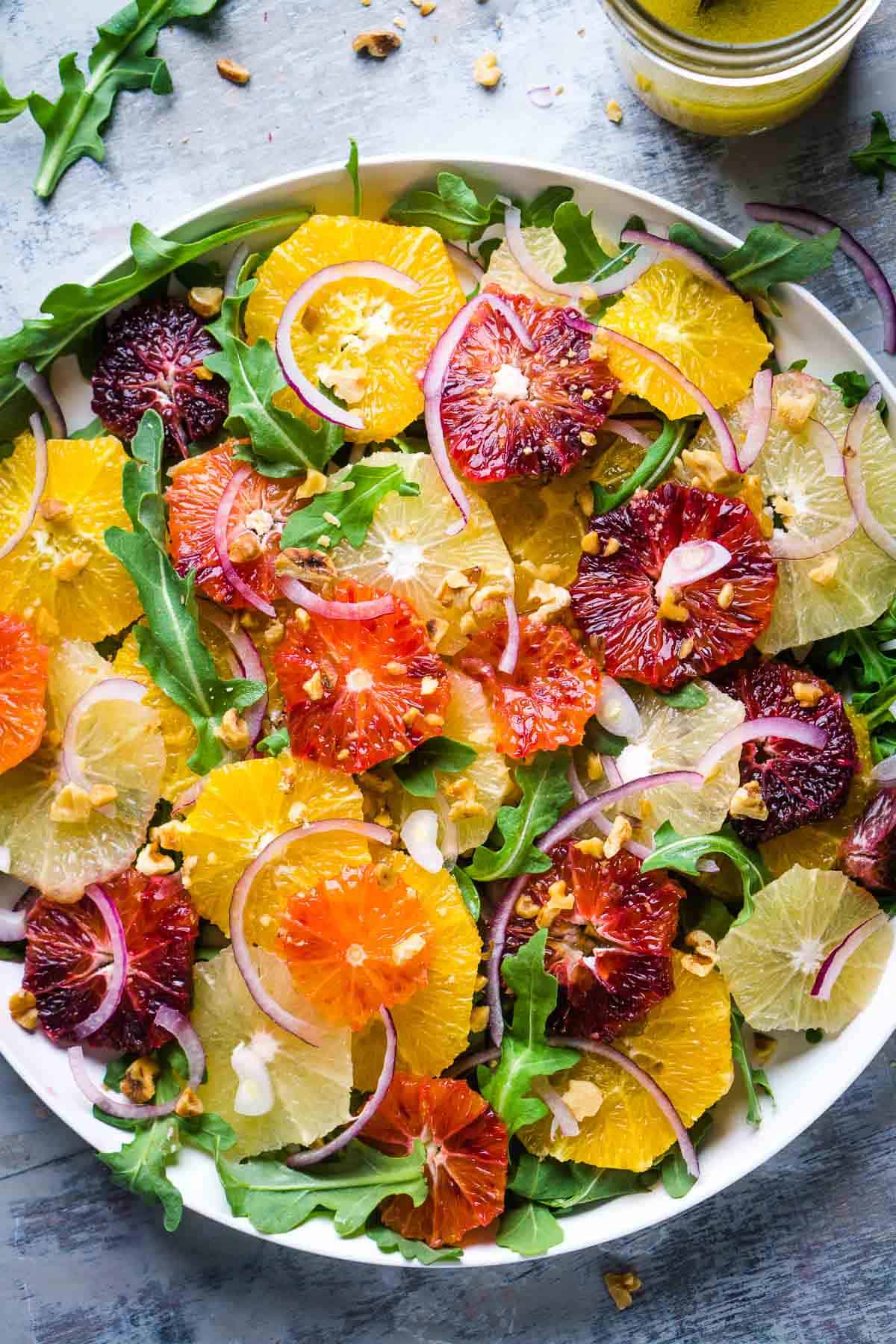 citrus salad on white serving platter next to dressing in mason jar