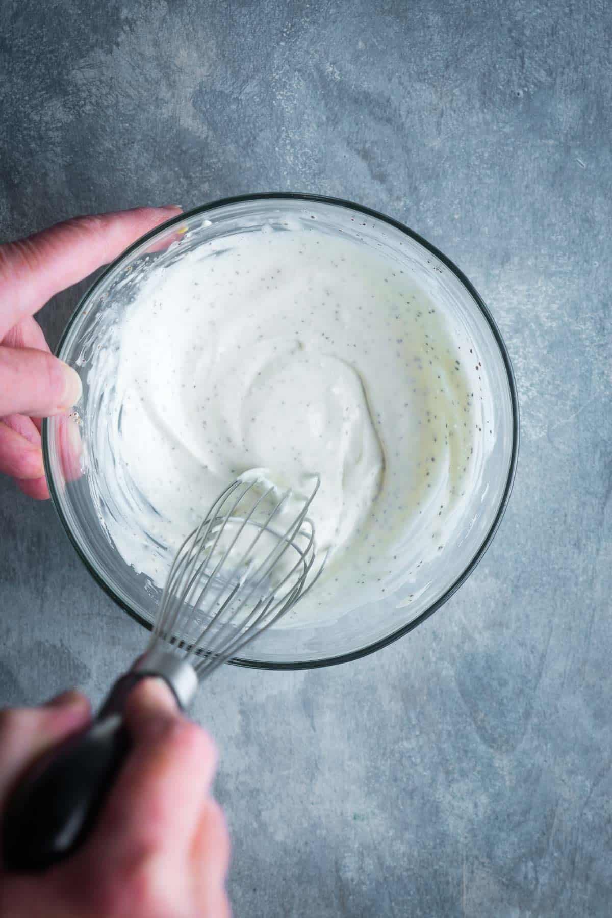 coleslaw salad dressing ingredients are whisked in glass mixing bowl