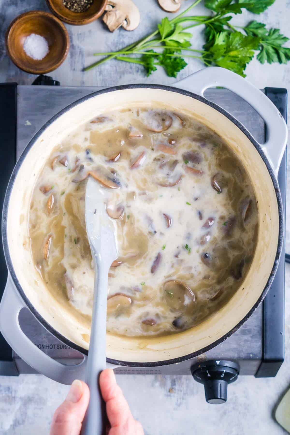silicone spatula stirs mushroom soup ingredients in soup pot