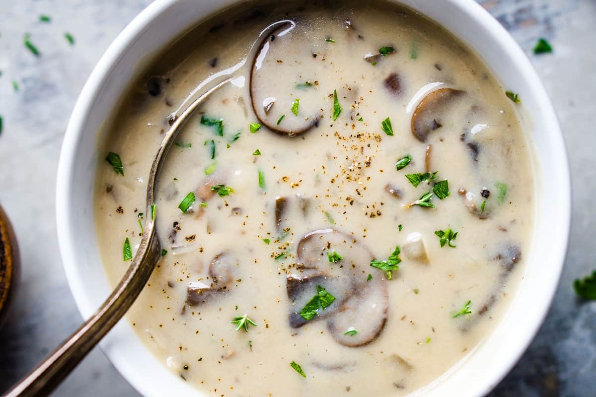 cream of mushroom soup in white bowl with soup spoon