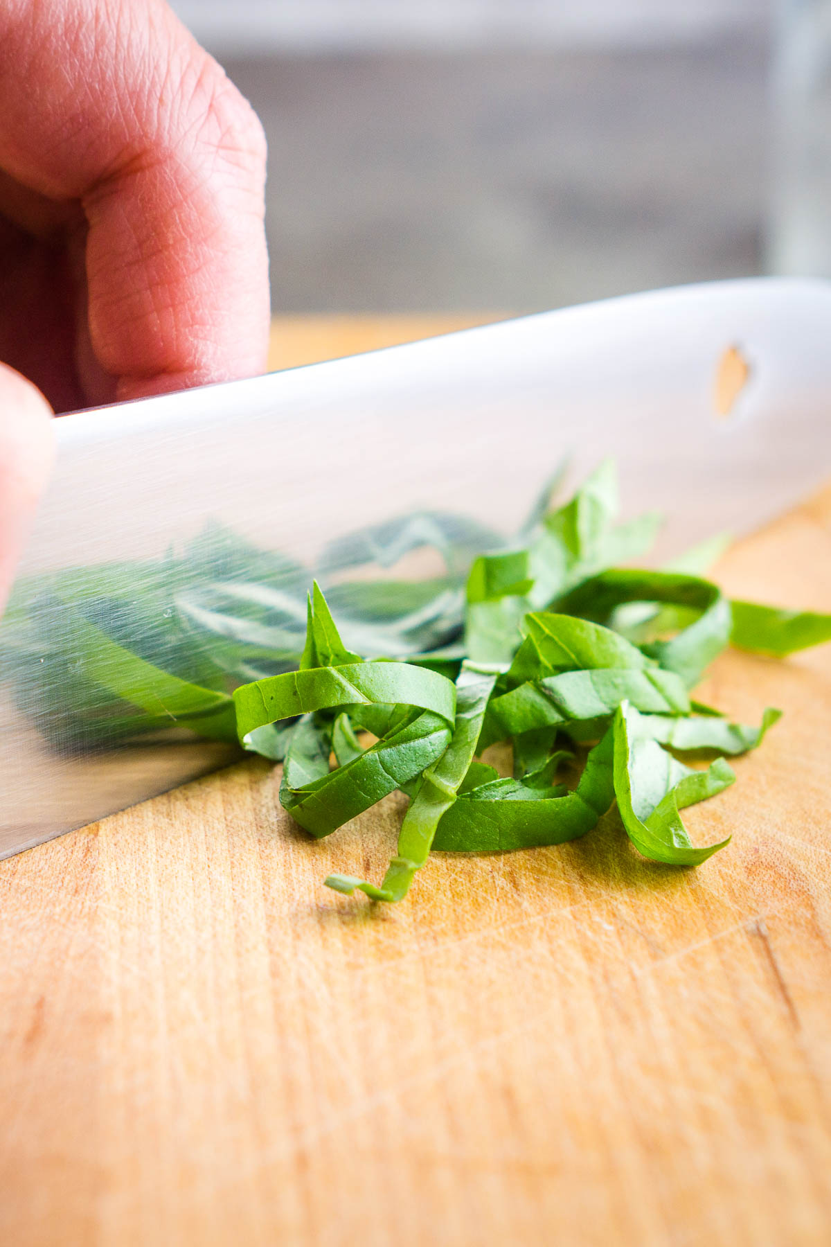 fresh basil is being chopped with chefs knife
