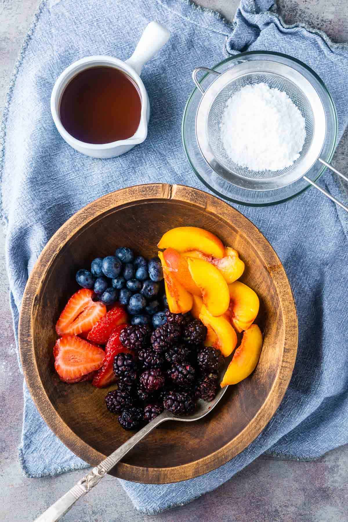 dutch baby toppings: fresh fruit, powdered sugar, and maple syrup in bowls