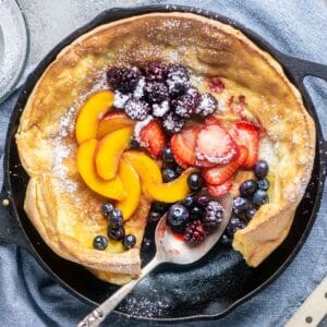 Fruit topped Dutch baby pancake in cast iron skillet