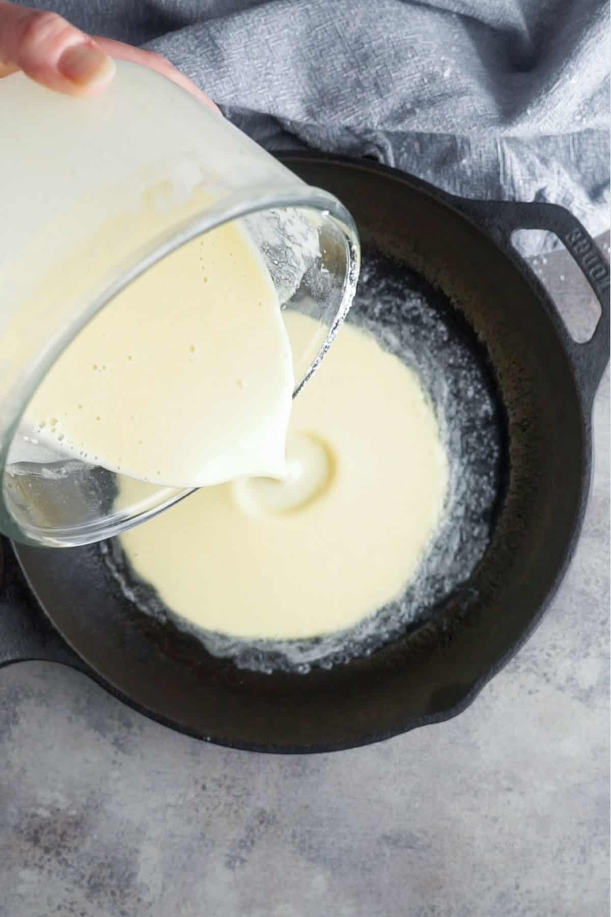 dutch baby batter is poured into cast iron skillet