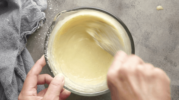 Whisking Dutch baby batter in glass bowl on gray surface