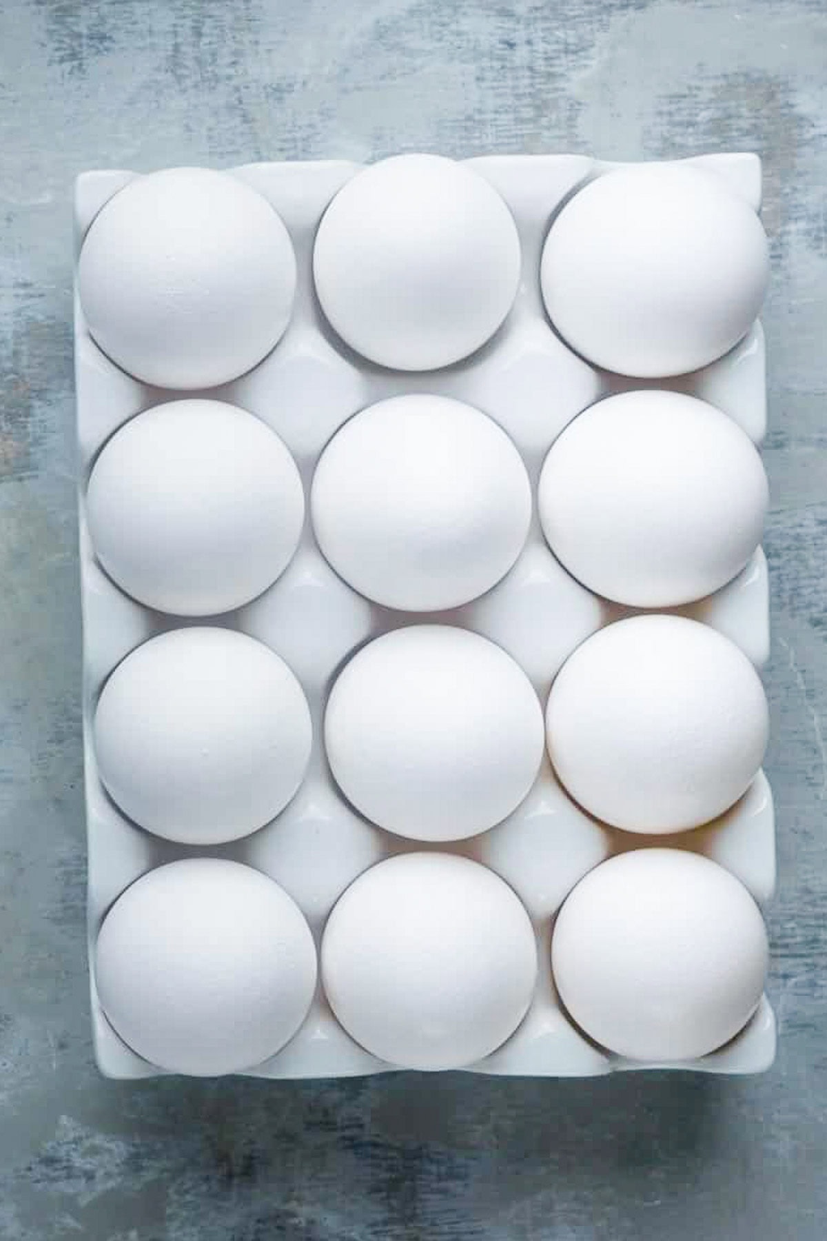 white eggs in white ceramic egg holder on gray surface
