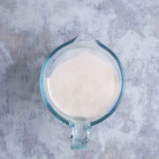 Overhead shot of bloomed yeast in water in glass measuring cup.