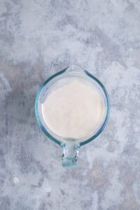 Overhead shot of bloomed yeast in water in glass measuring cup.