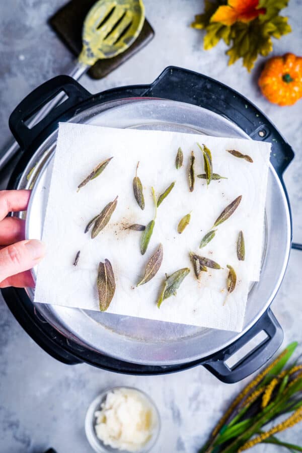 fried sage leaves on paper towel lined plate over prep area