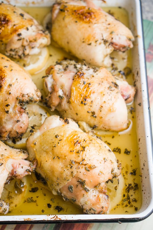 Greek lemon chicken thighs on white baking sheet