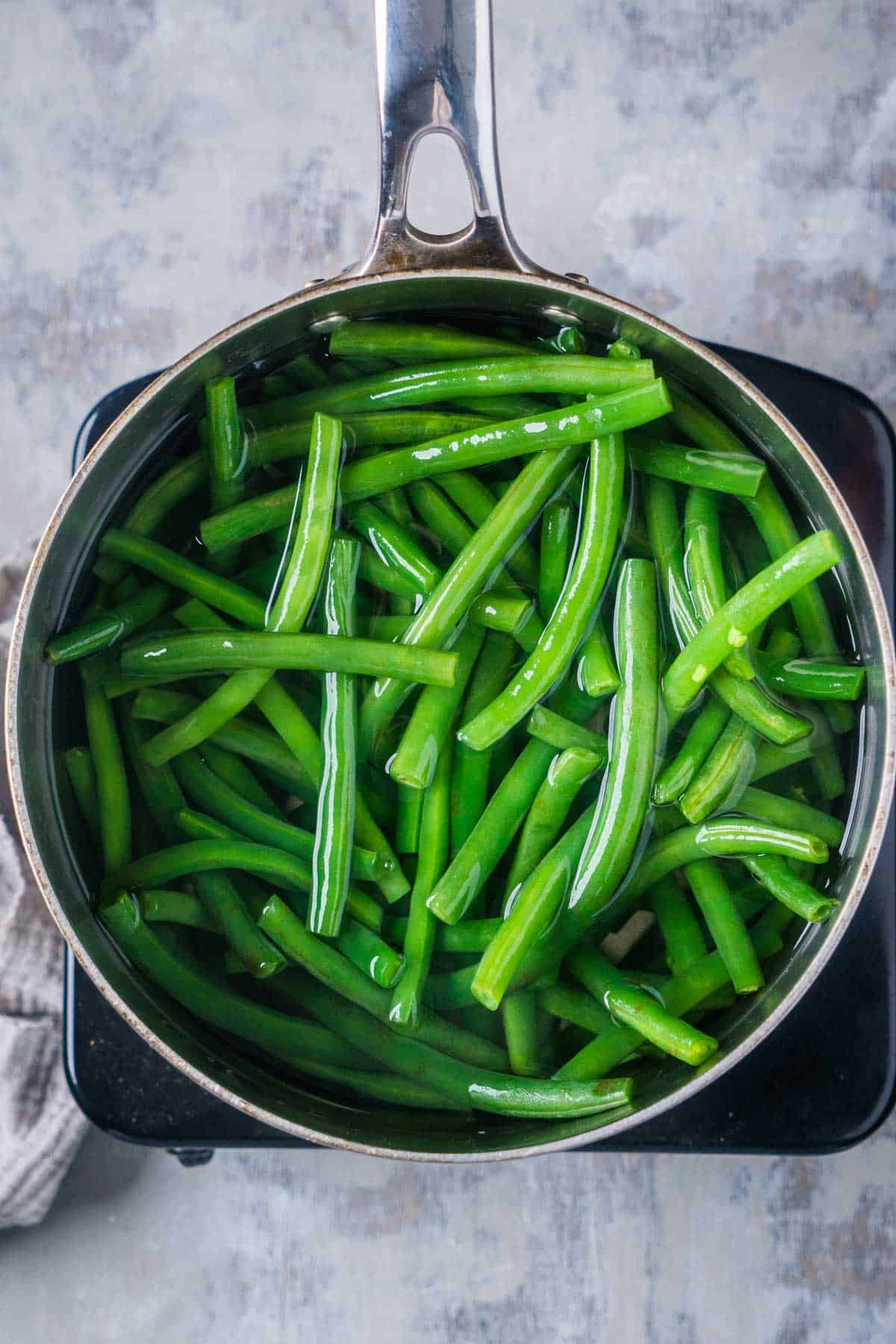 fresh green beans boiling in sauce pot over single burner