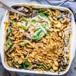 creamy green bean casserole with crispy French onion topping in white baking dish with serving spoon