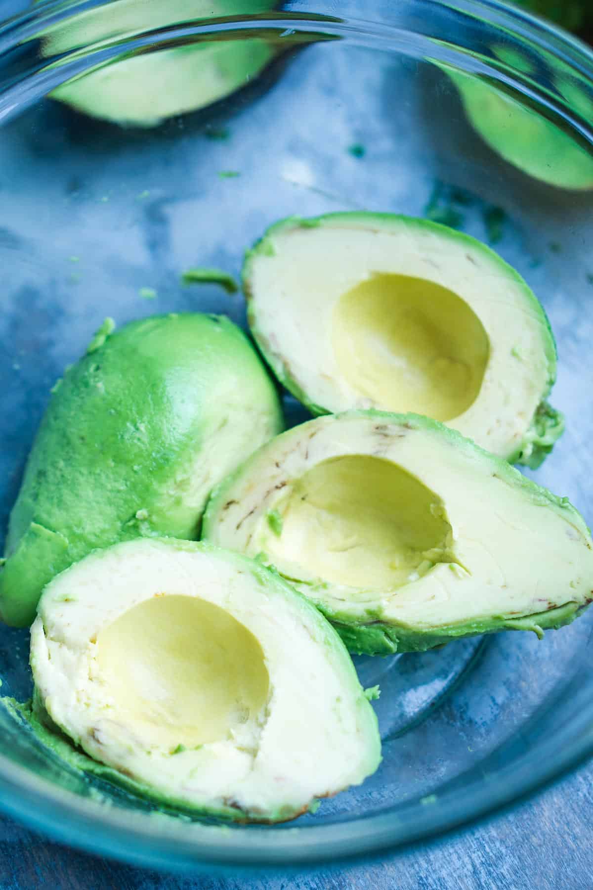 pitted avocado halves in glass mixing bowl