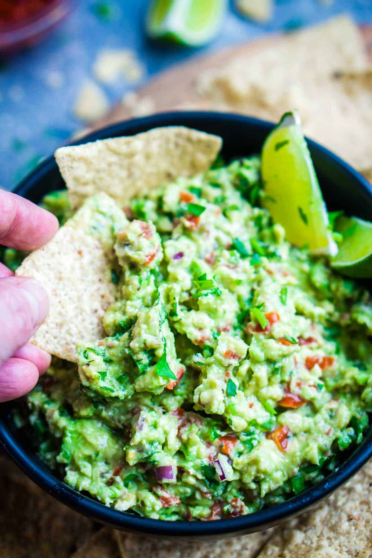 tortilla chip is dunked into bowl of guacamole