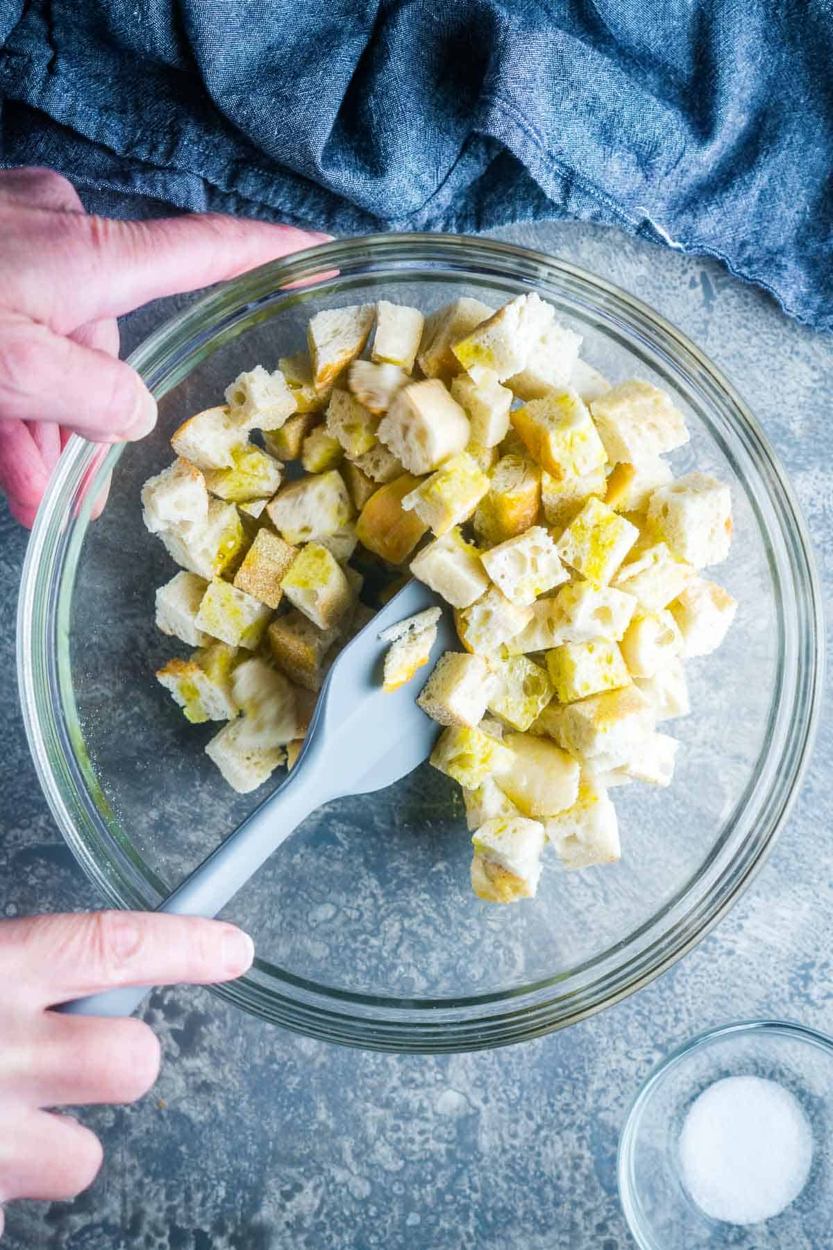 spatula stirs croutons in glass mixing bowl