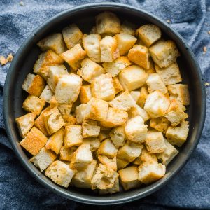 Homemade croutons in gray ceramic bowl on blue linen