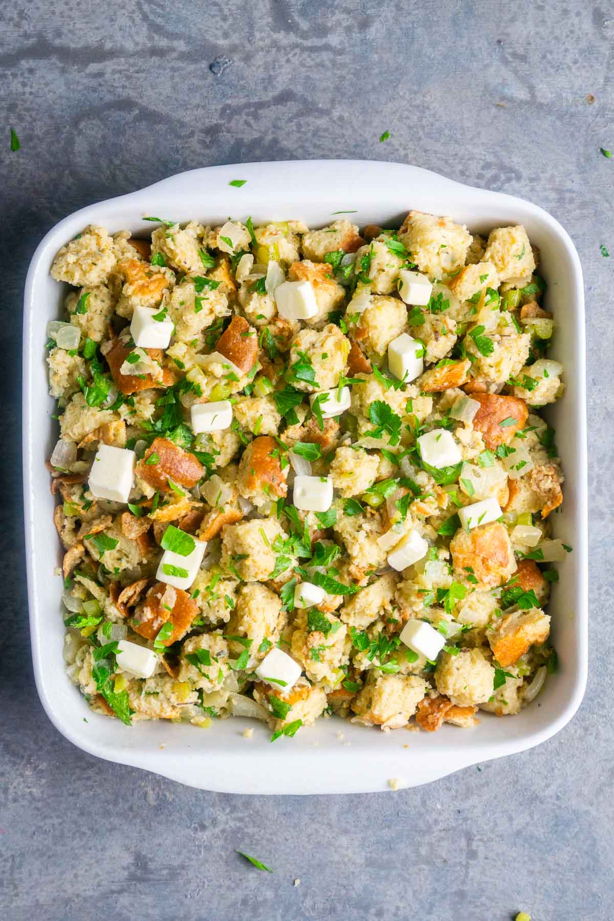 unbaked stuffing with butter cubes in white baking dish