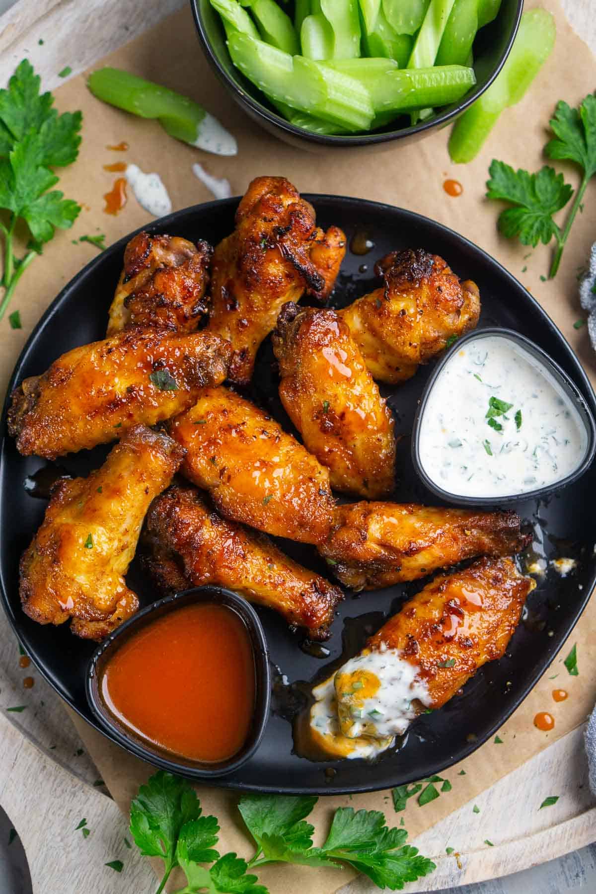 platter of honey hot wings with ramekins of buffalo sauce and ranch dressing