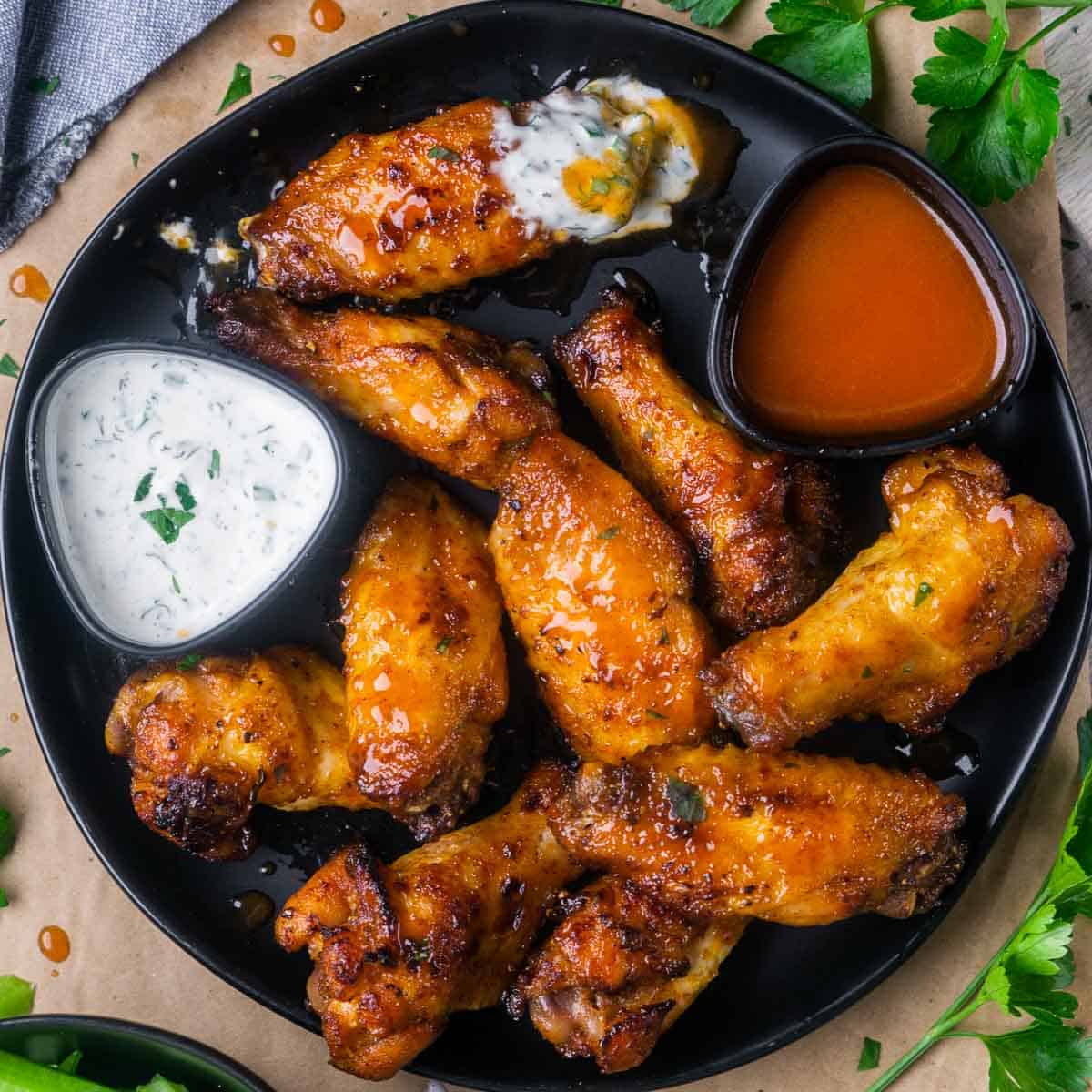 platter of honey hot wings with ramekins of buffalo sauce and ranch dressing
