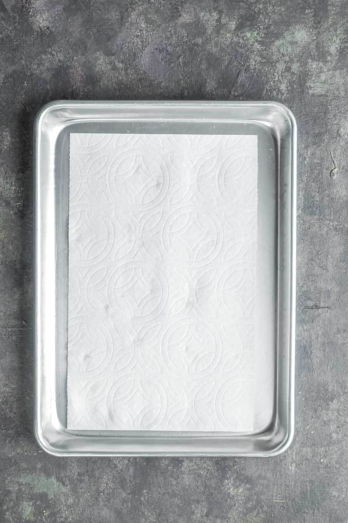 A metal baking tray lined with a white paper towel.