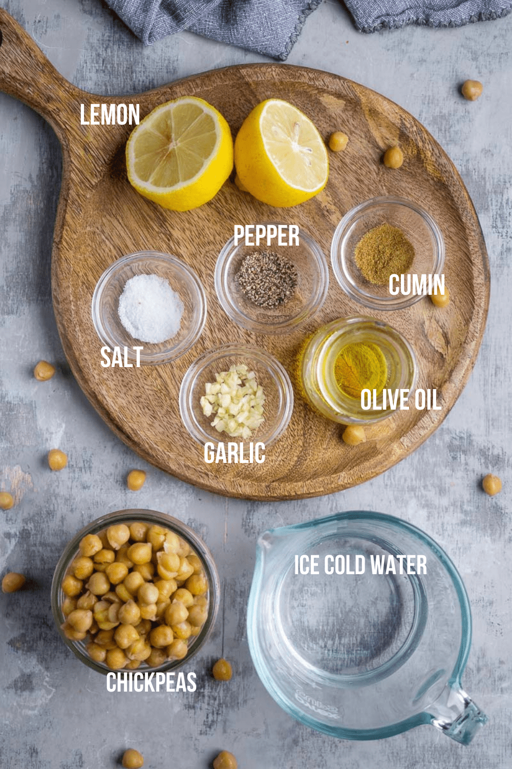 hummus ingredients in glass bowls displayed on a cutting board and countertop