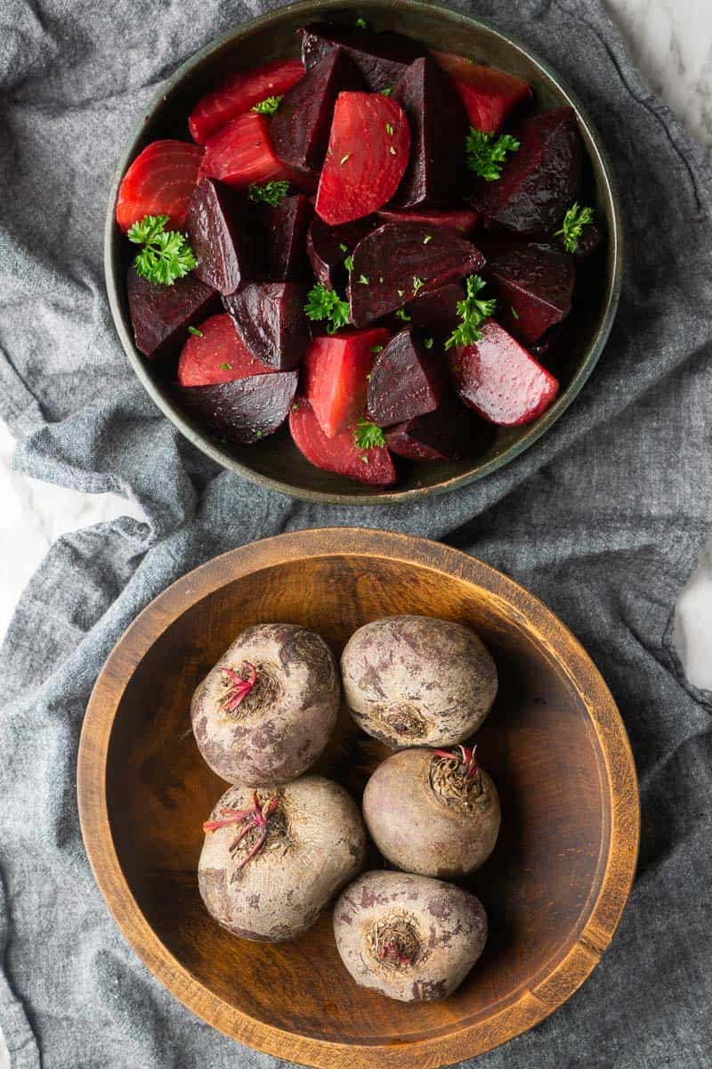 bowl of chopped, pressure cooked beets next to bowl of whole beets uncooked with skin on
