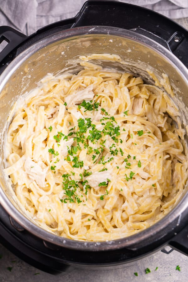Instant pot chicken Alfredo in the pot garnished with chopped parsley and ready to serve