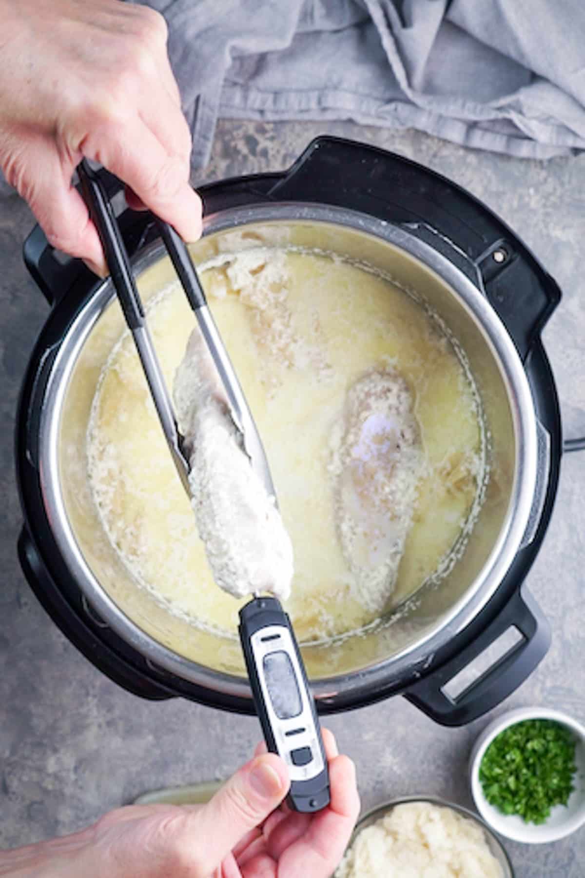 meat thermometer inserted in cooked chicken breast inside Instant Pot