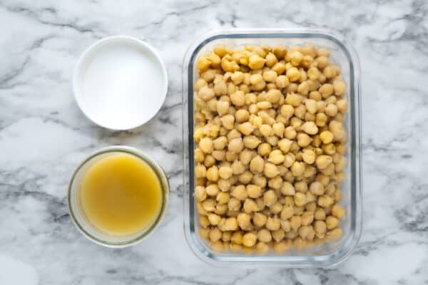 Overhead view of pressure cooker chickpeas and chickpea juice in glass meal prep containers