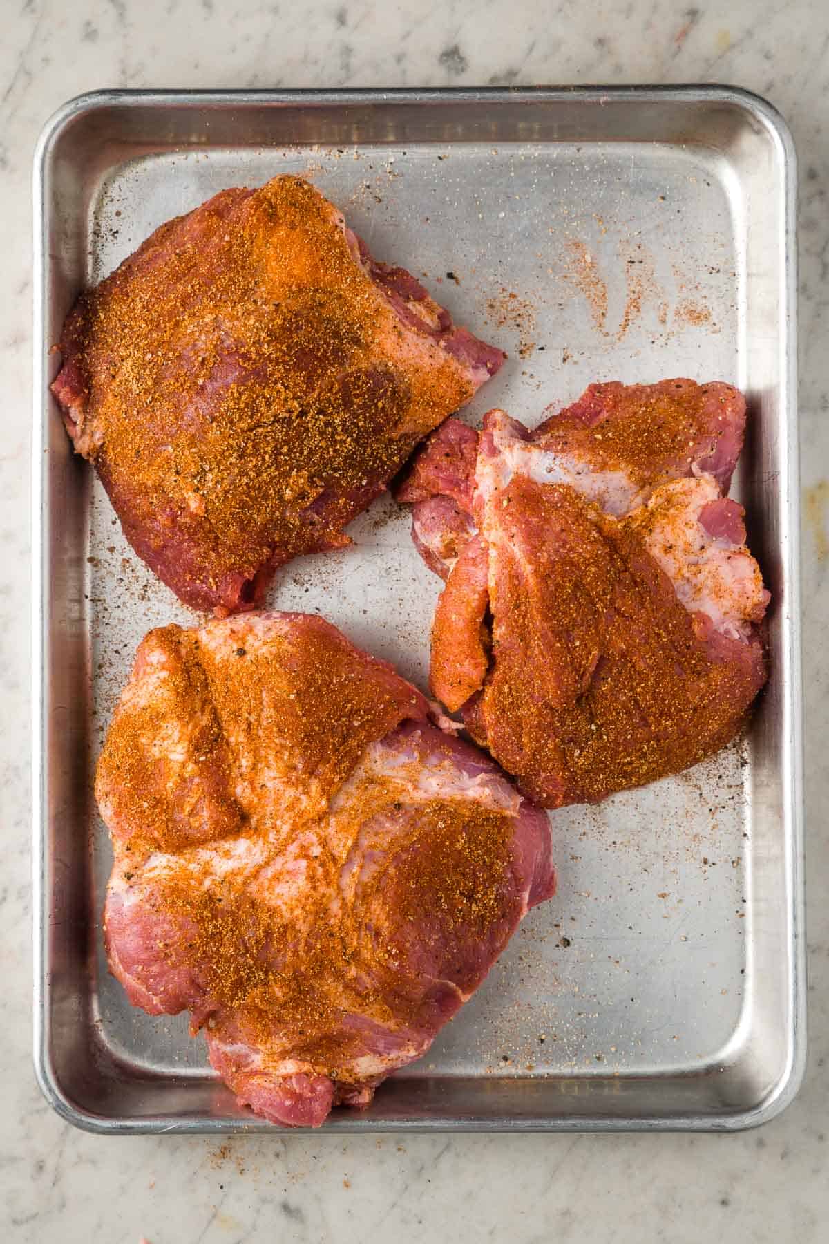 spice rubbed raw pork on baking sheet