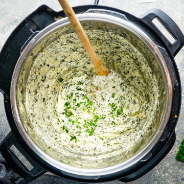 spinach artichoke dip being stirred by wooden spoon in the Instant Pot