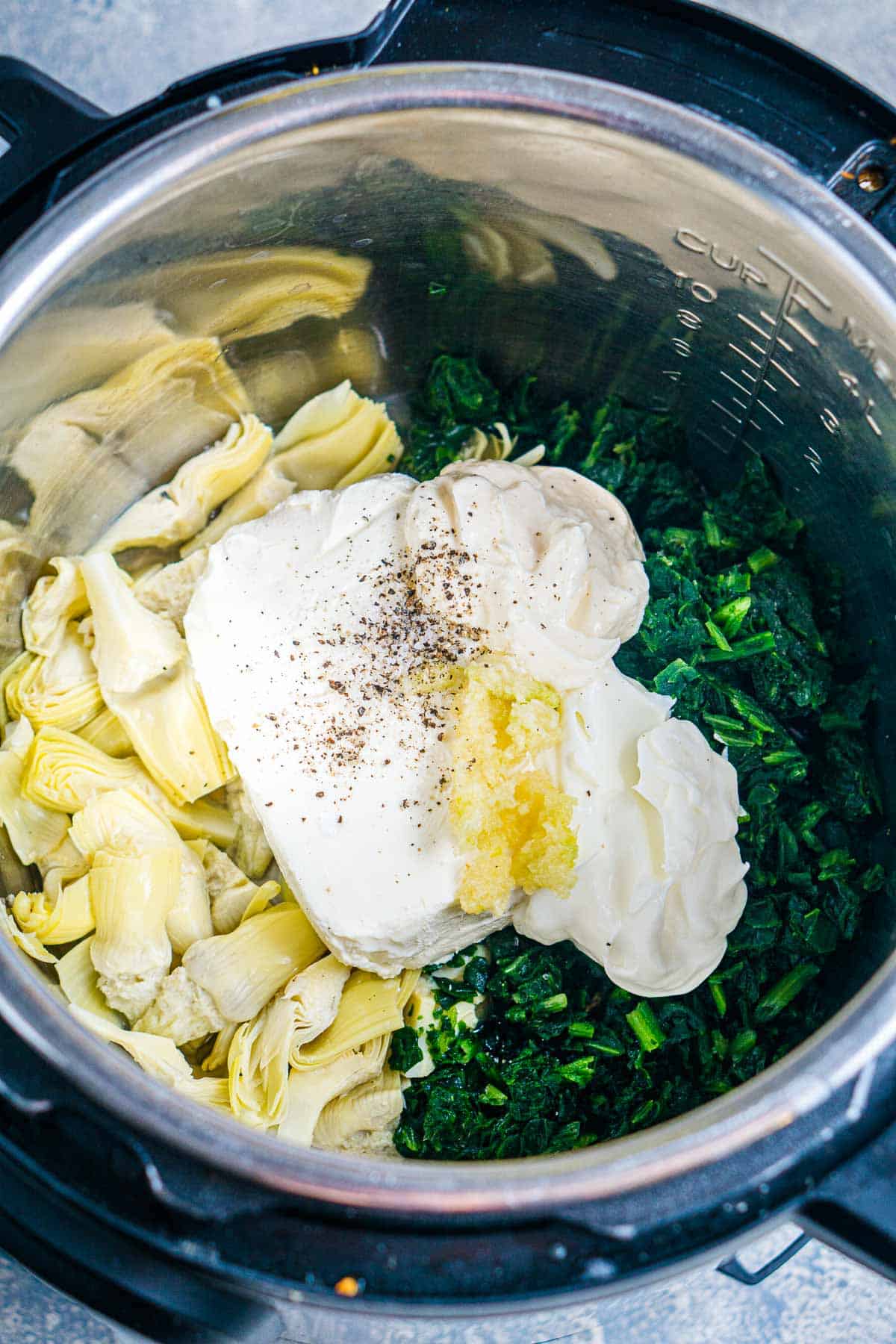 spinach artichoke dip ingredients are layered in the instant pot before pressure cooking