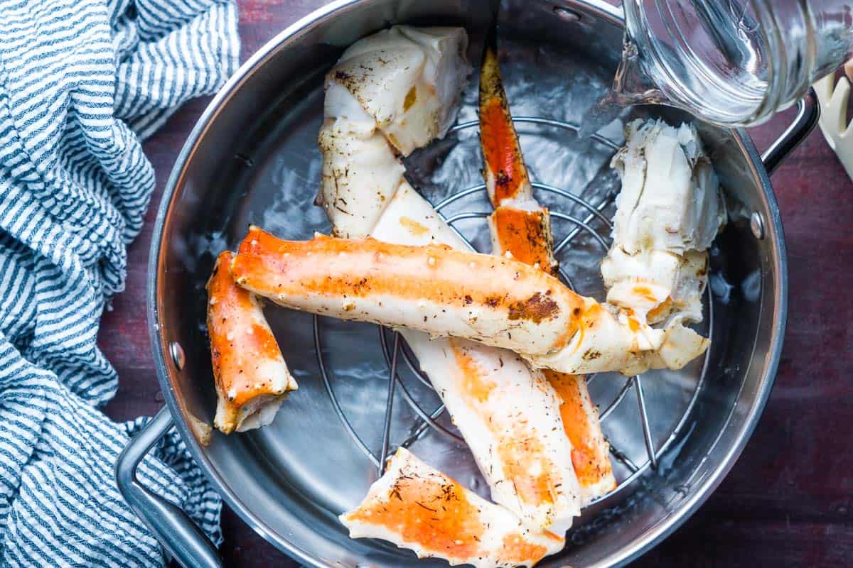 king crab legs on trivet in soup pot with water being added
