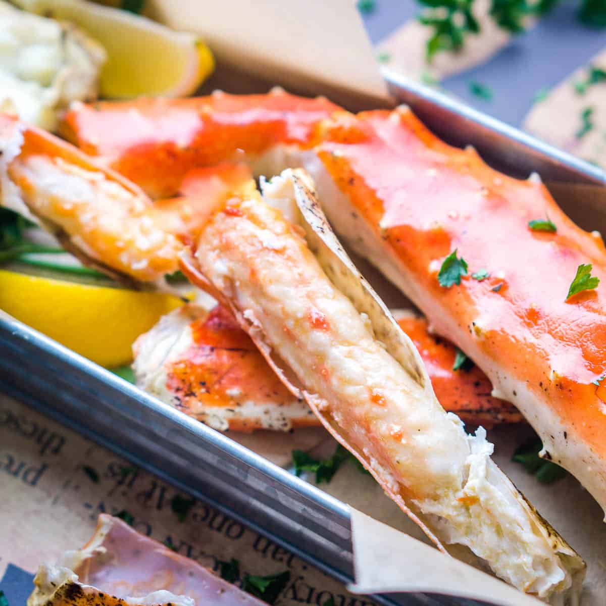 king crab legs in serving tray with parsley and lemon wedges