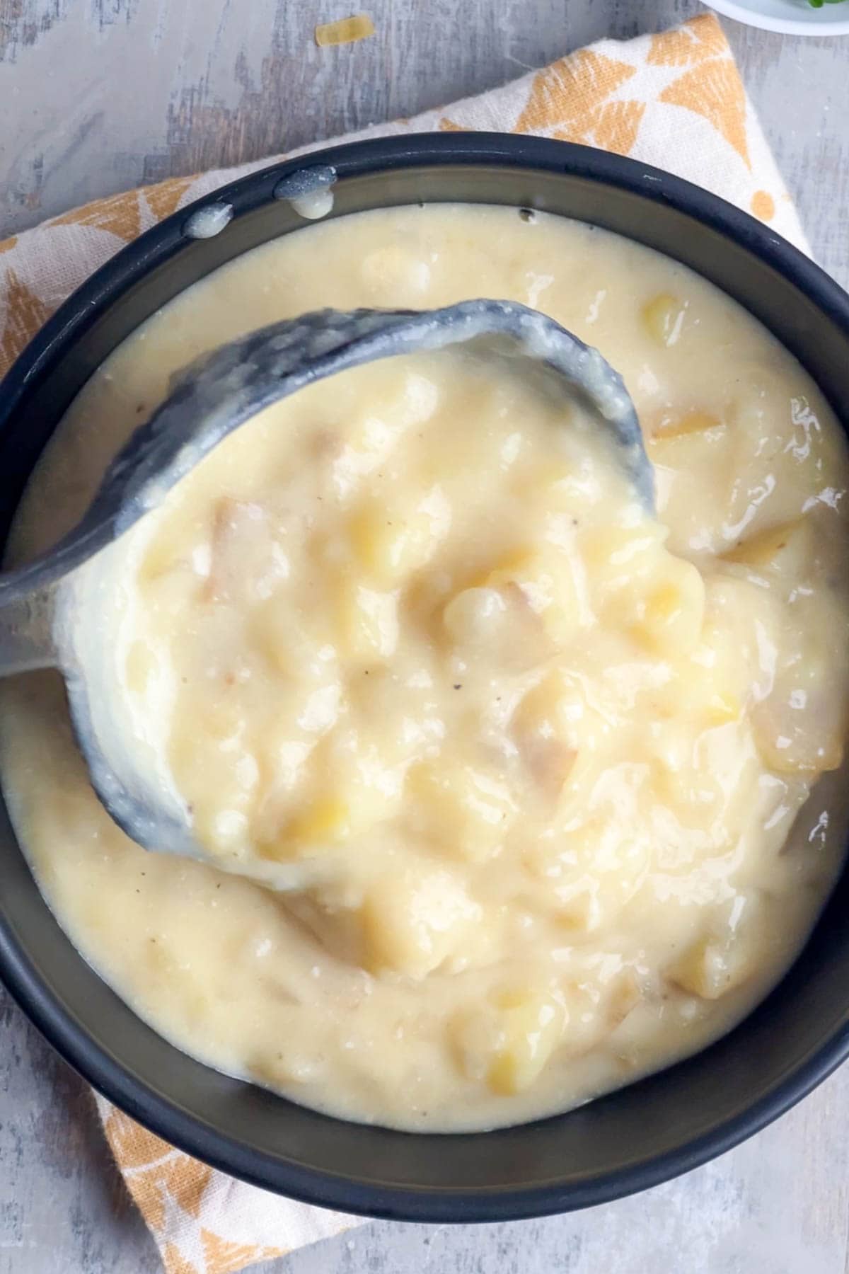 Chunky, creamy potato soup is ladled into a black bowl.