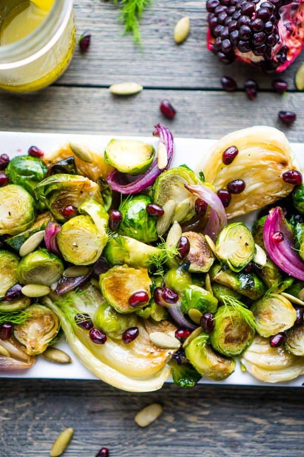 Brussels sprouts, red onion, fennel, pomegranate, and pepitas on white plate on gray background