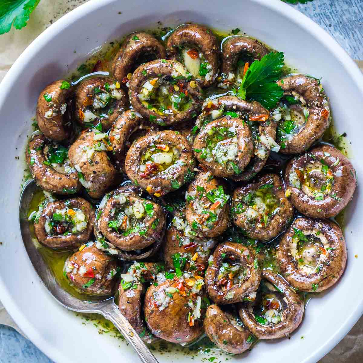marinated mushrooms in white serving bowl with serving spoon