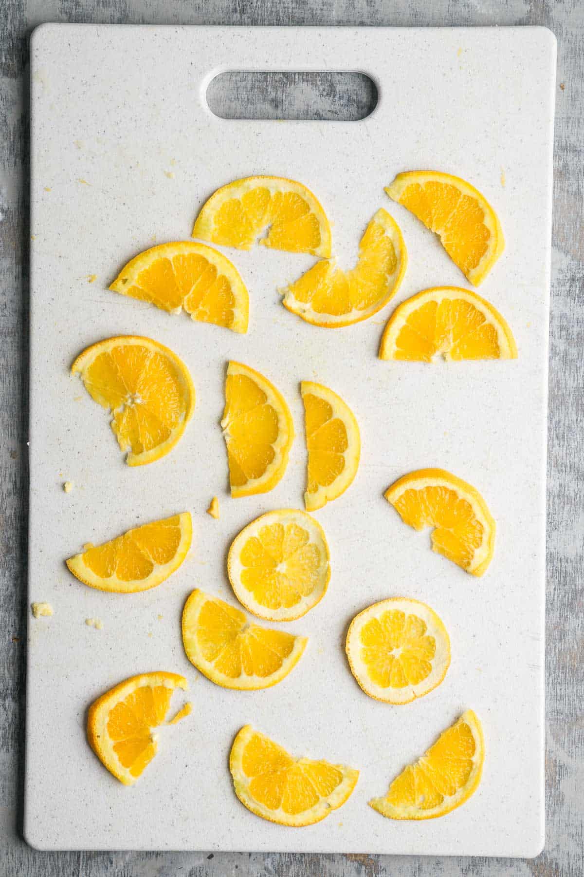 Very thinly sliced orange pieces on a cutting board.