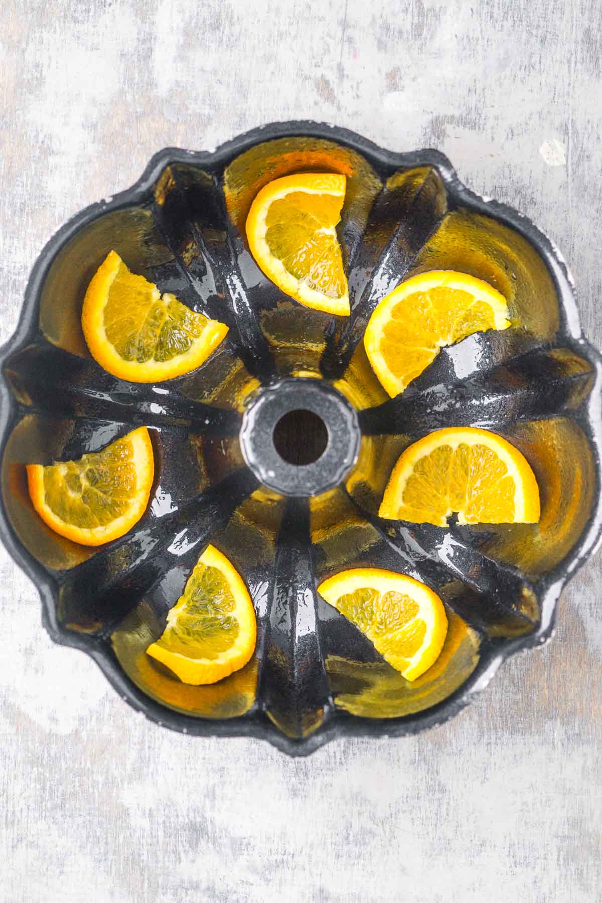 Bundt cake pan with very thinly sliced orange pieces placed throughout.