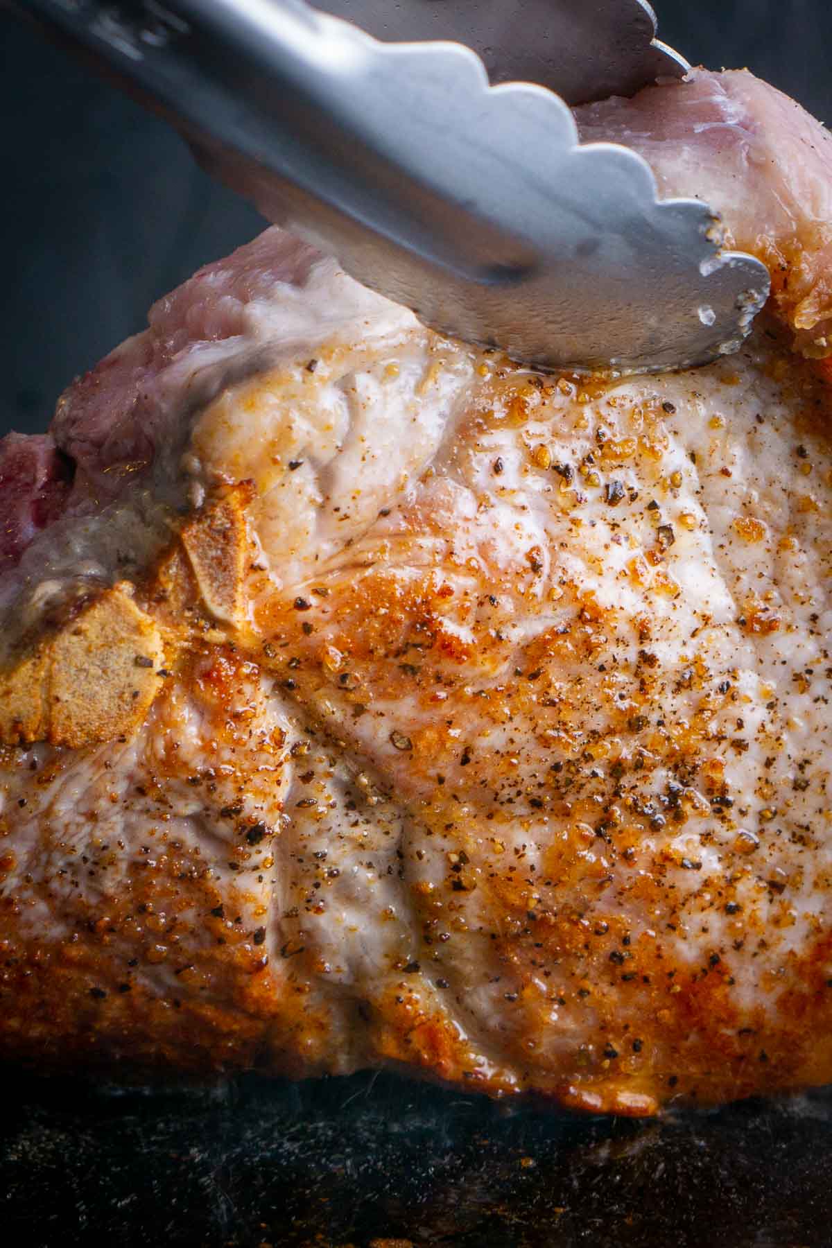 tongs lift seared pork chop