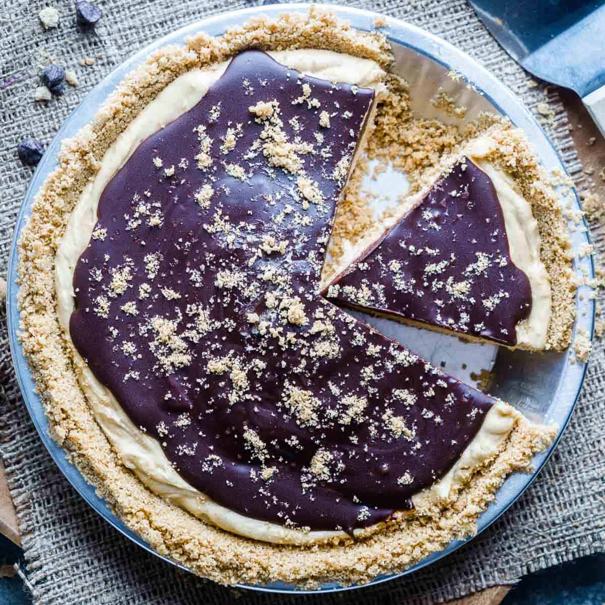 peanut butter pie with chocolate topping in pie tin with one slice removed