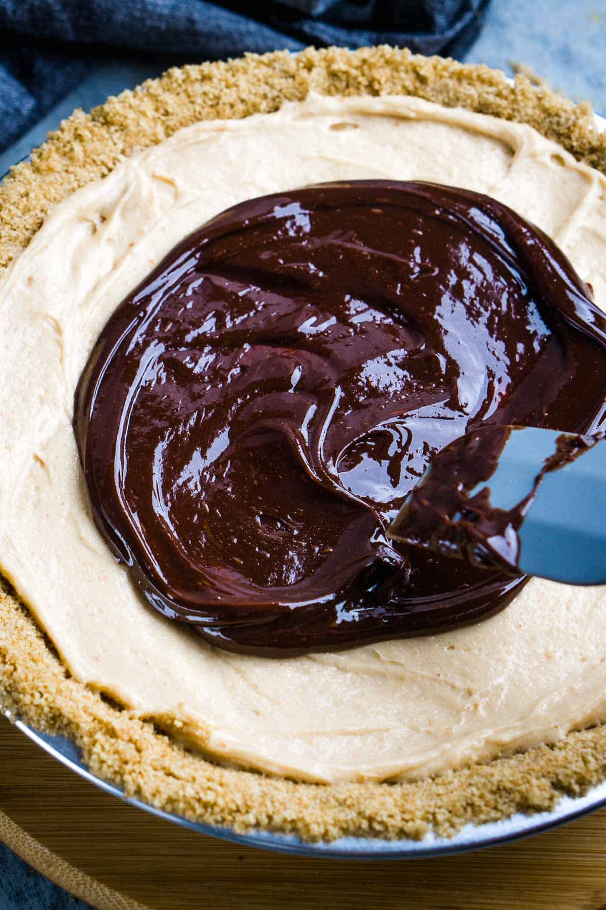 spatula spreads chocolate topping over peanut butter pie filling