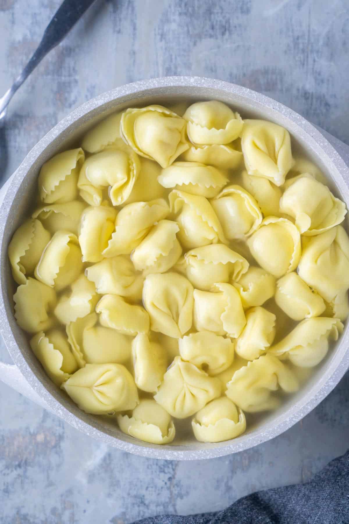 cooked tortellini in gray soup pot