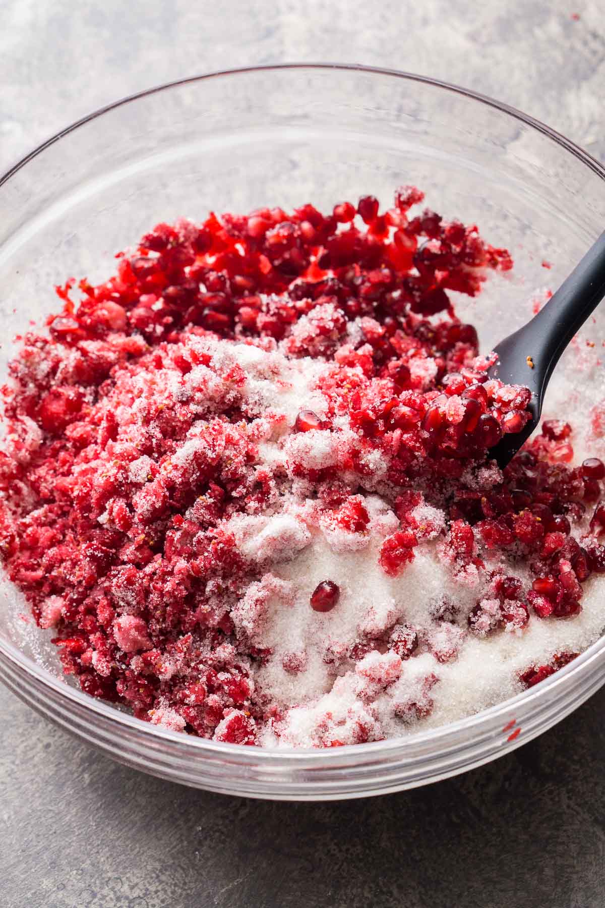 3 ingredient cranberry relish with pomegranate might just become your new favorite Thanksgiving holiday sauce. It's so easy to blend raw cranberries, fold in sugar and pomegranate, and let it macerate a few days in the refrigerator until it become juicy and so mouthwatering. You'll love how pomegranate cranberry relish tastes when it's served alongside holiday turkey, mashed potatoes, and gravy. spatula tosses pomegranate cranberry relish ingredients in glass bowl