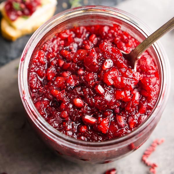 pomegranate cranberry relish in glass jar with serving spoon