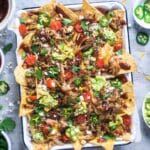 pulled pork nachos on parchment-lined white baking sheet