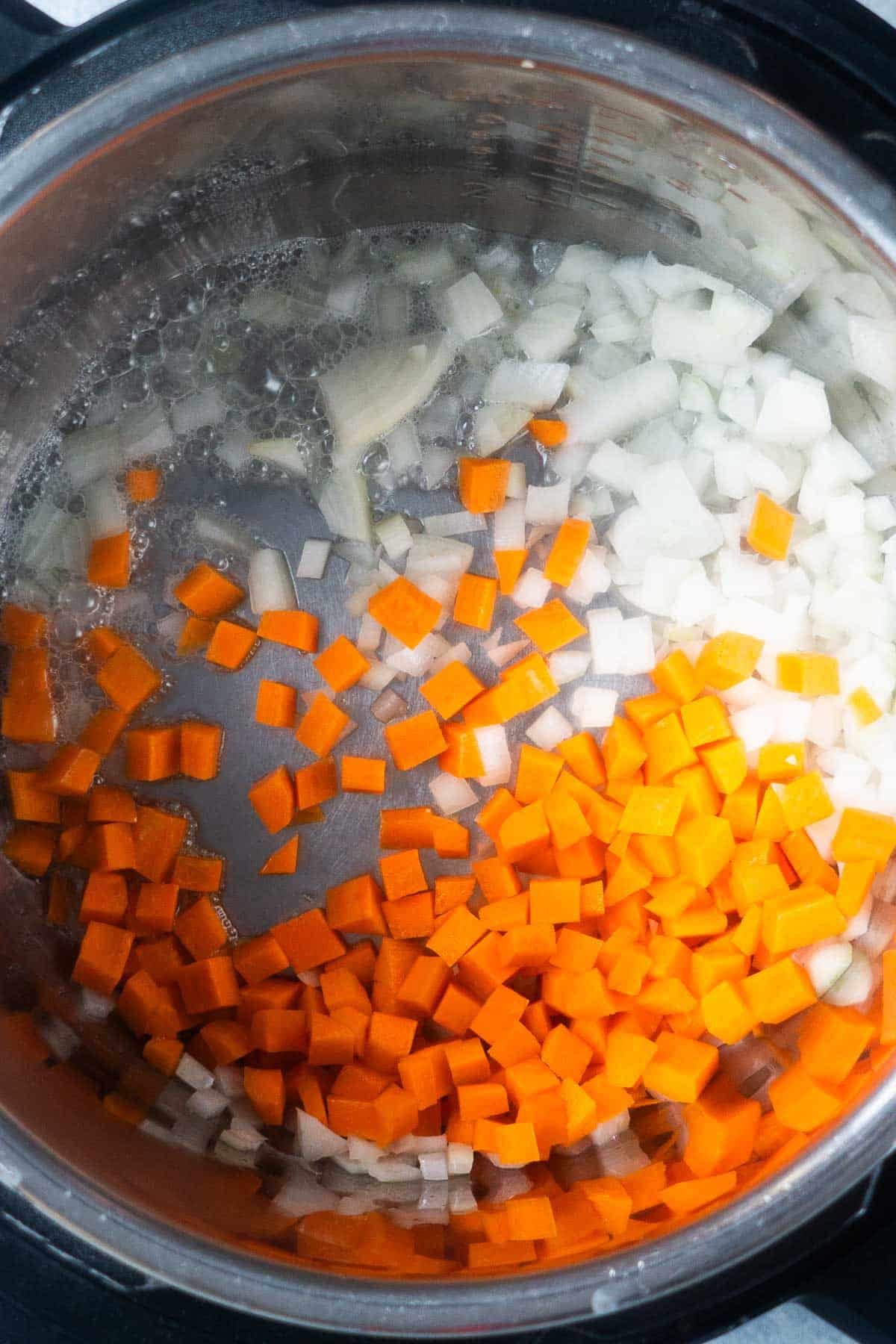 carrots and onions are sauteed in soup pot