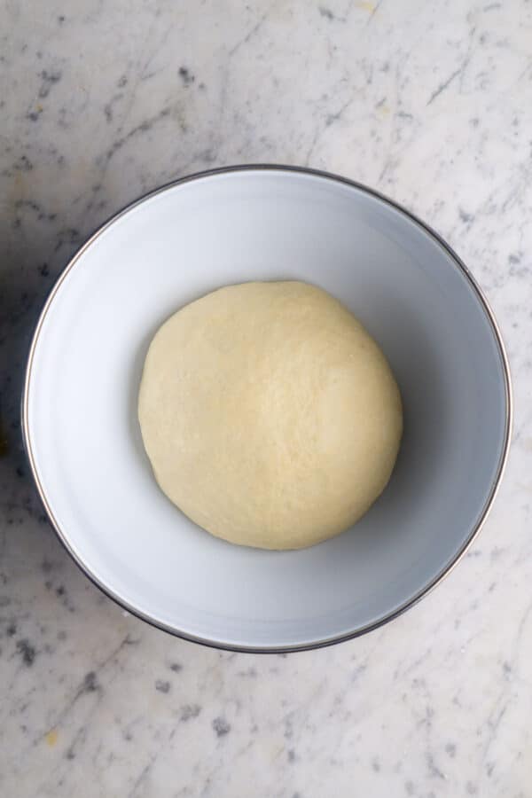 cinnamon roll dough in white bowl on white marble surface