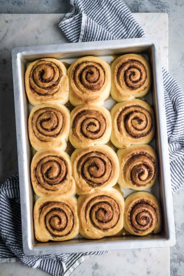 baked cinnamon rolls in metal baking pan over striped linen